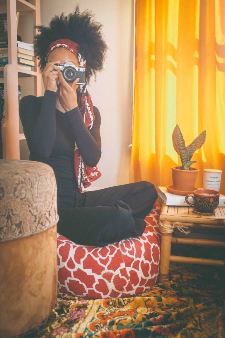 bohemian lifestyle artist taking self portrait with camera in warm light studio