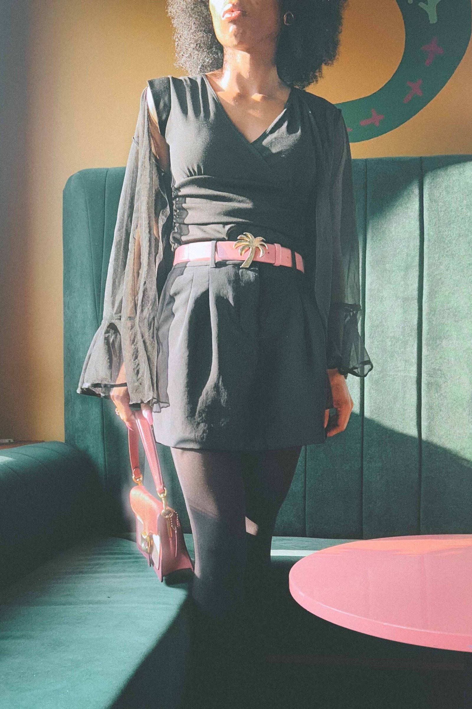 Black dress with sheer sleeves styled with bubblegum pink Palm Angels belt and pink designer handbag, thrifted chic outfit.