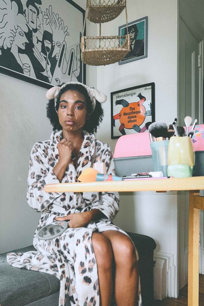 Reflective moment before the show — sitting in a leopard robe with natural curls and a bare face during my artist ritual.