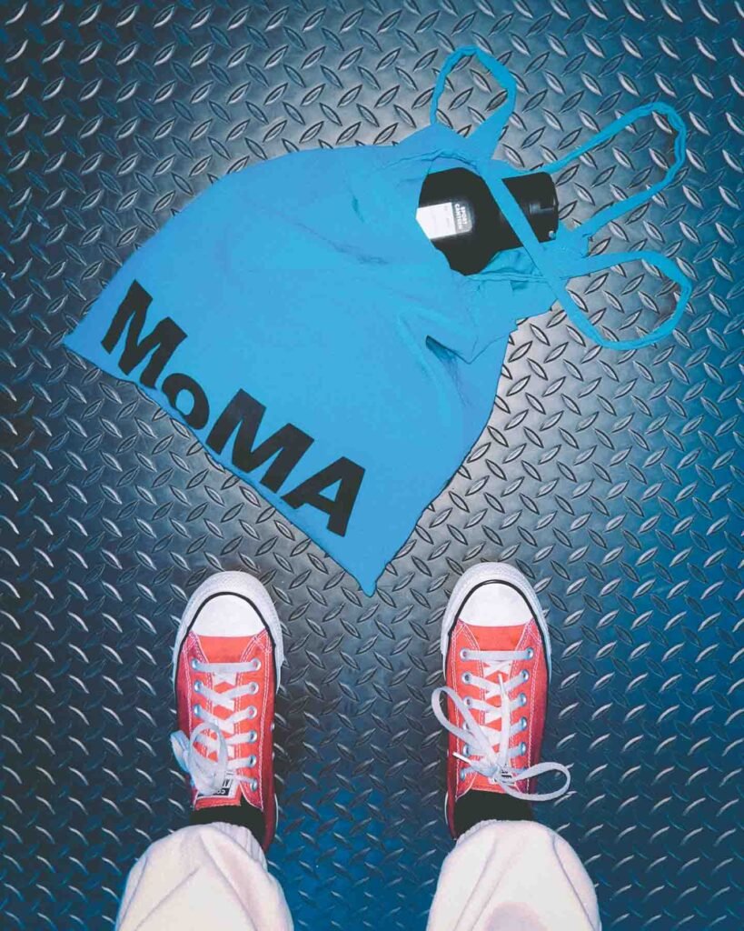 Red sneakers beside a blue MoMA tote on a textured gym floor — blending art and discipline during the process of starting over after burnout.