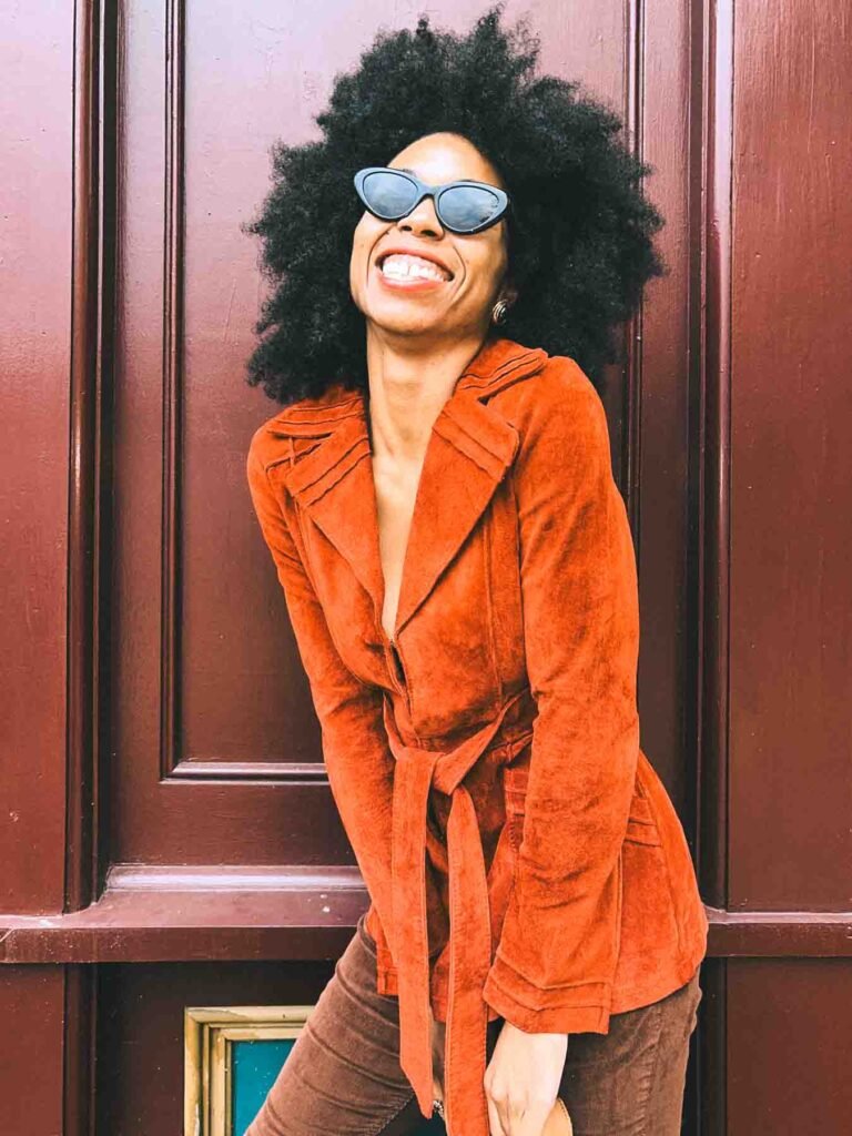 Bohemian blogger wearing a burnt orange suede jacket and cat-eye sunglasses in a fall outfit for an Inside My Closet feature.