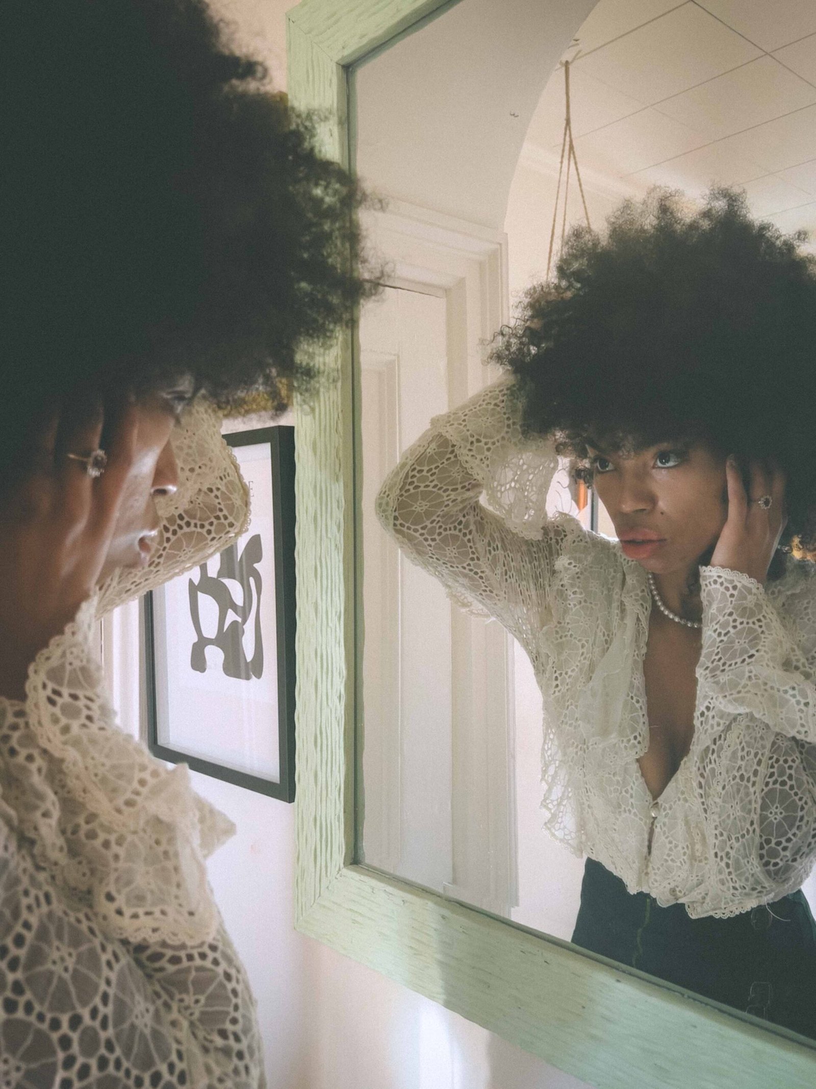 Bohemian woman adjusting her hair in the mirror, capturing holiday loneliness and self-reflection during Thanksgiving.