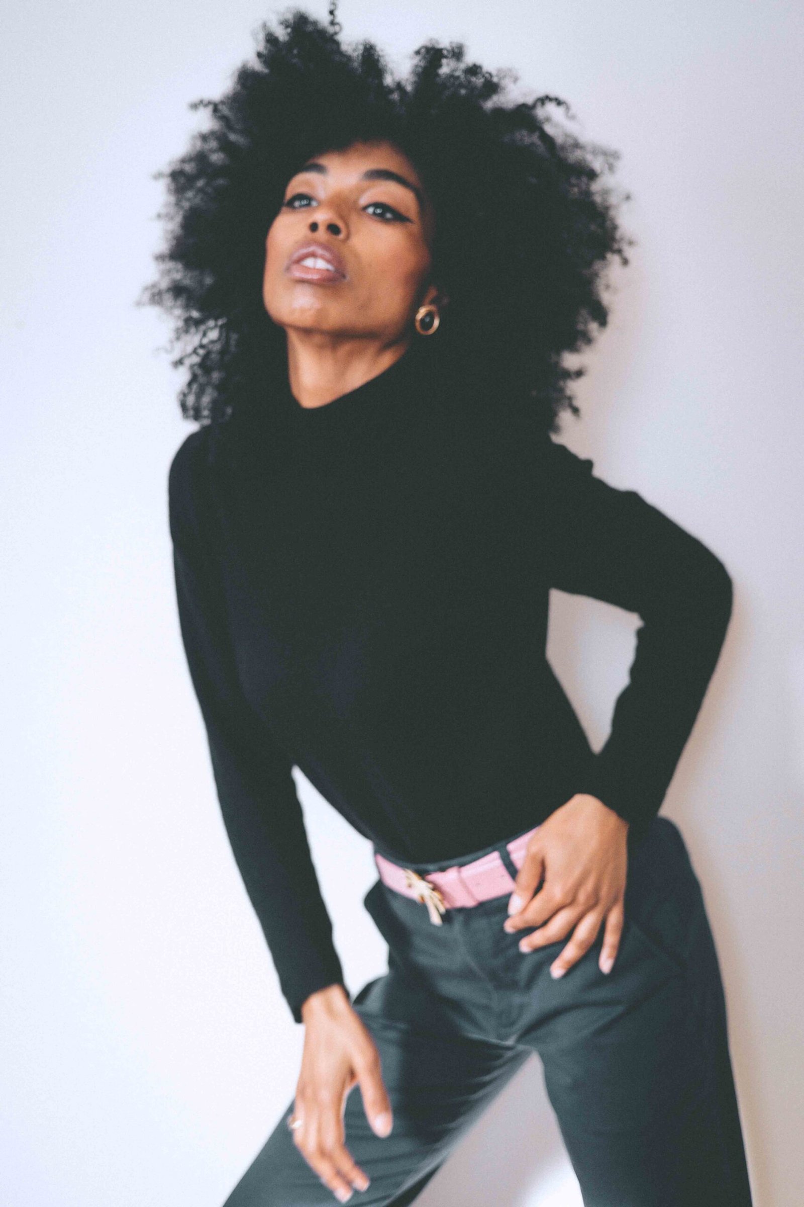 Minimalist winter outfit featuring a fitted black cashmere turtleneck and structured pants against a neutral backdrop