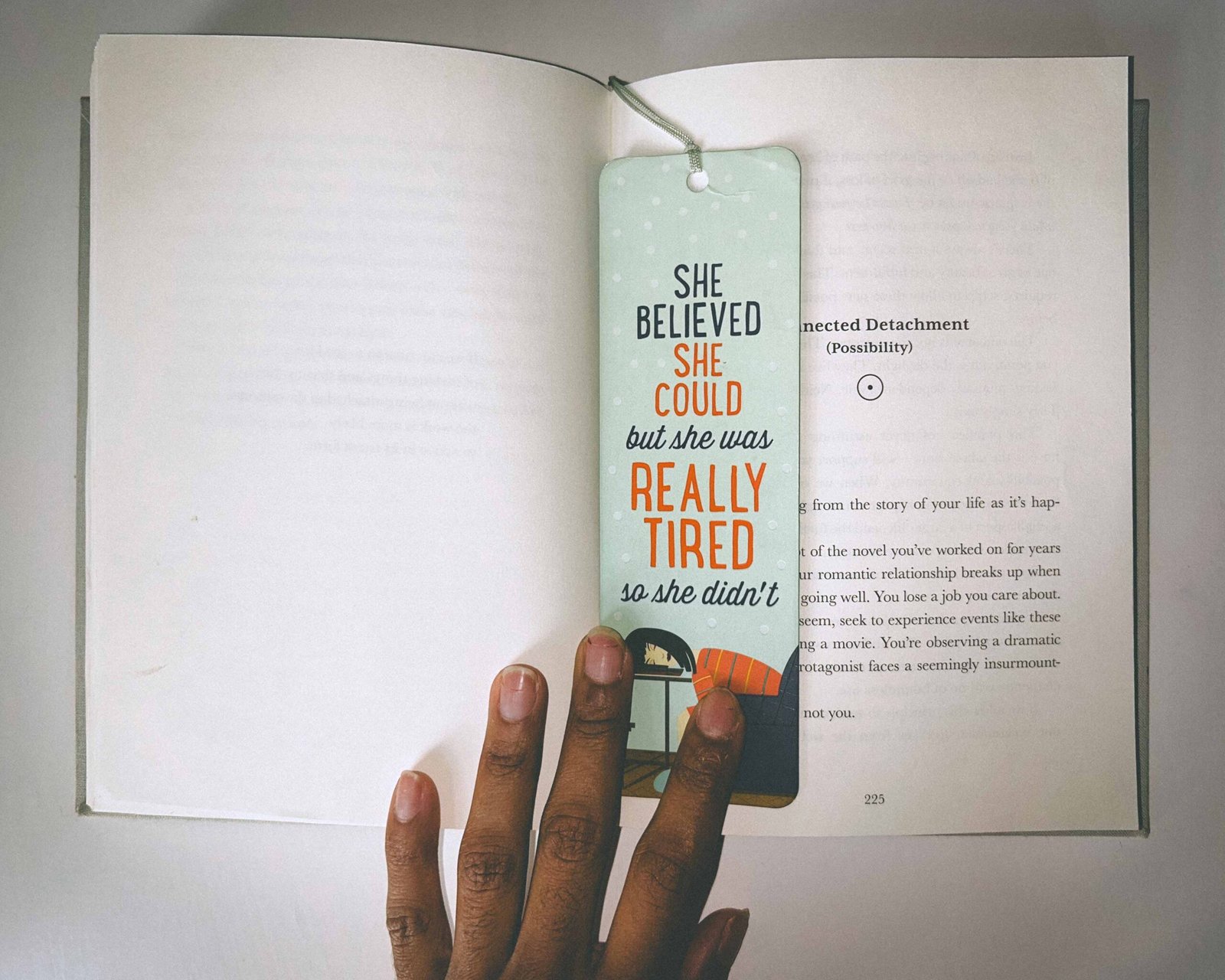 Bookmark reading “She believed she could but she was really tired so she didn’t” resting inside Rick Rubin’s book “The Creative Act,” shown on a clean white table.