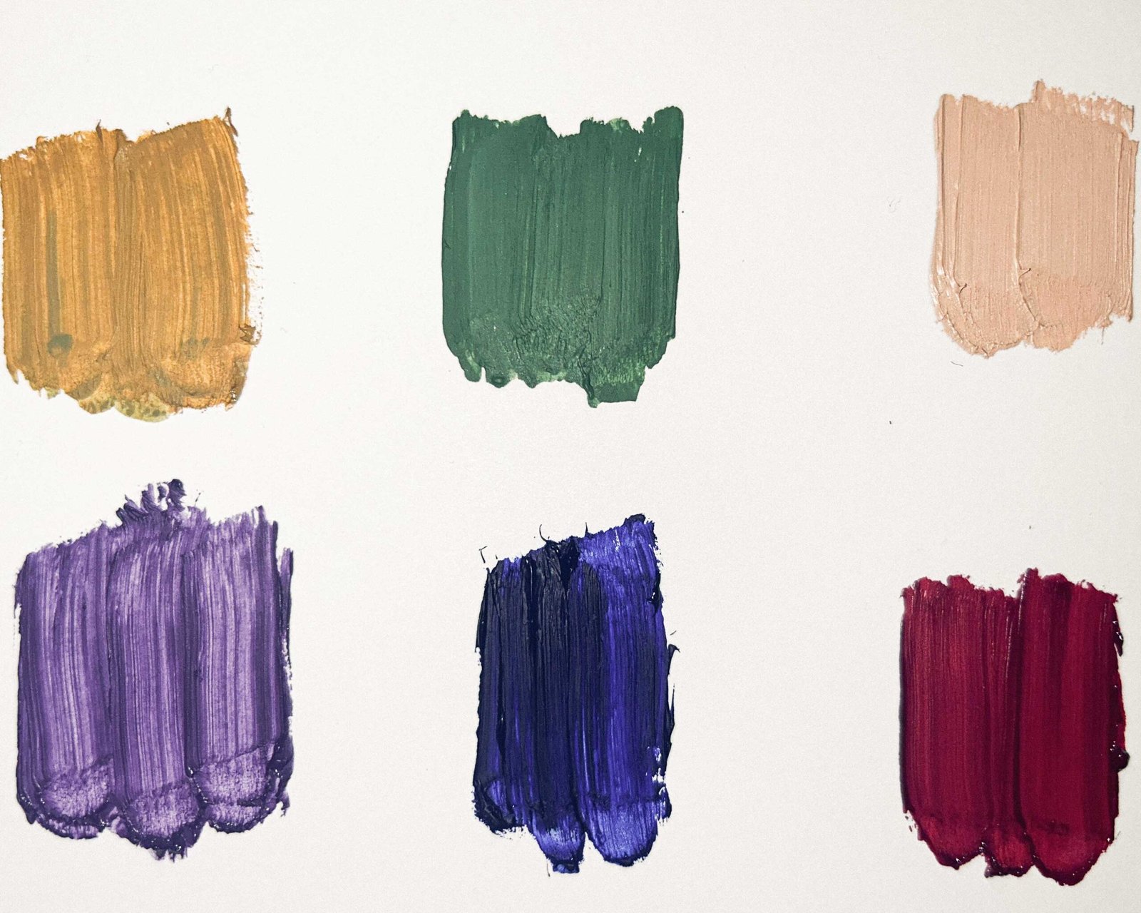 Six bold oil paint color swatches—including mustard yellow, green, peach, violet, ultramarine, and burgundy—testing hues for a new art series.