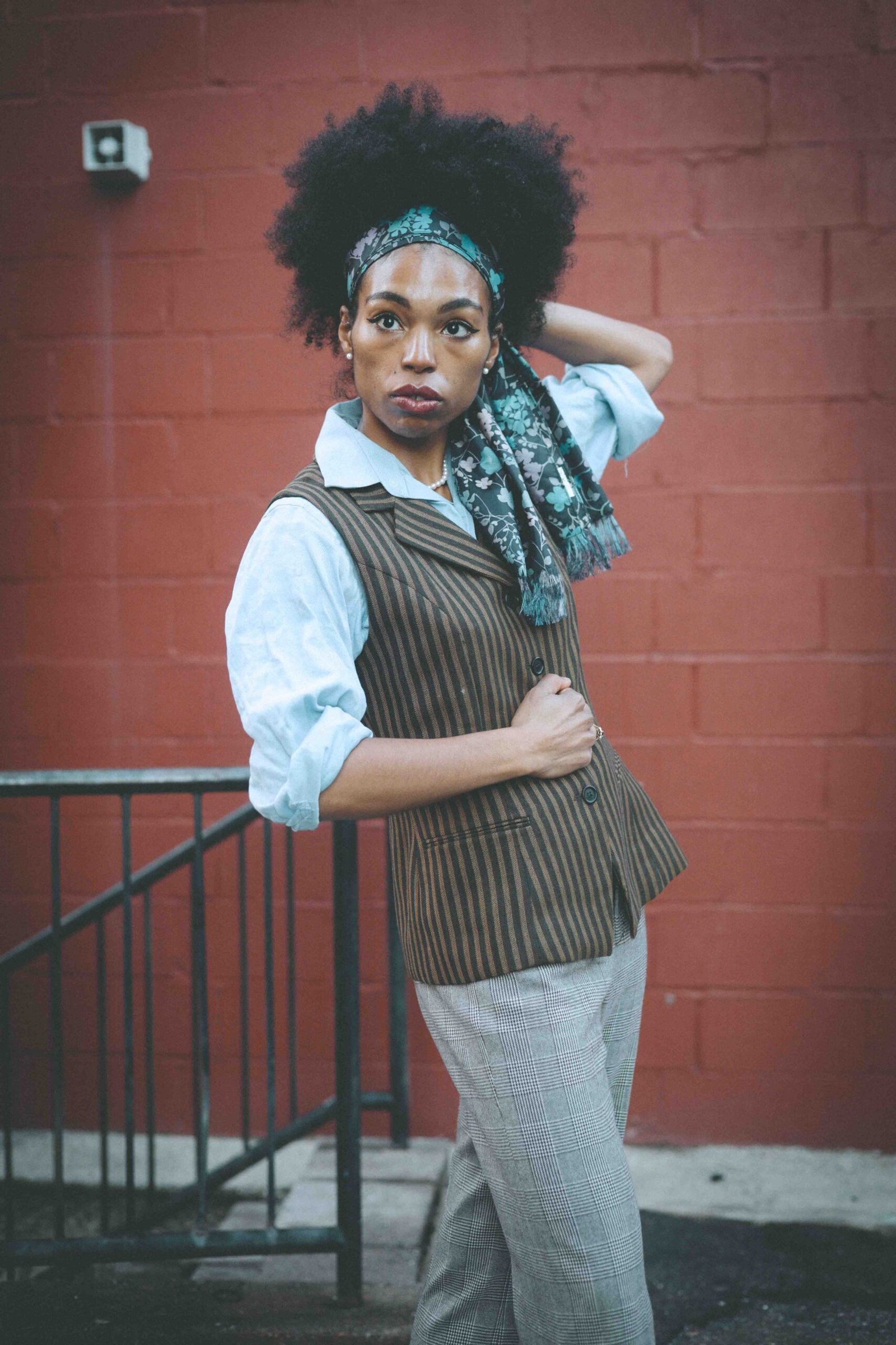 Brown striped vest and rolled-sleeve button-down shirt paired with gray plaid trousers, styled with a patterned scarf for a classic boho-luxe winter outfit.