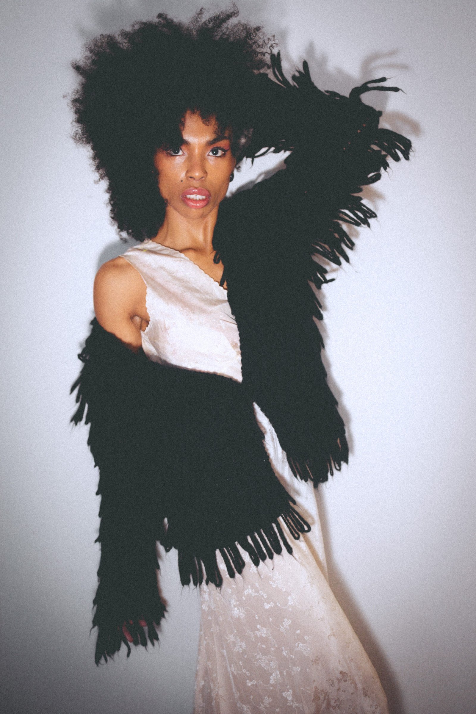 Editorial portrait of art girl in a fringed black jacket and slip dress, blending softness and strength in private glamour styling.