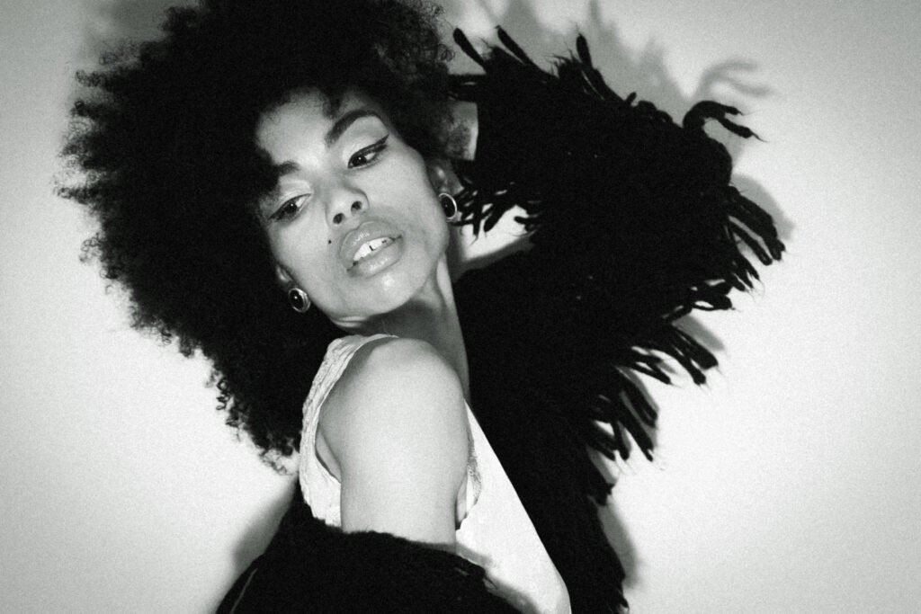 Black and white art girl winter portrait featuring a vintage slip dress and textured outer layer, photographed indoors with dramatic shadow and an editorial feel.