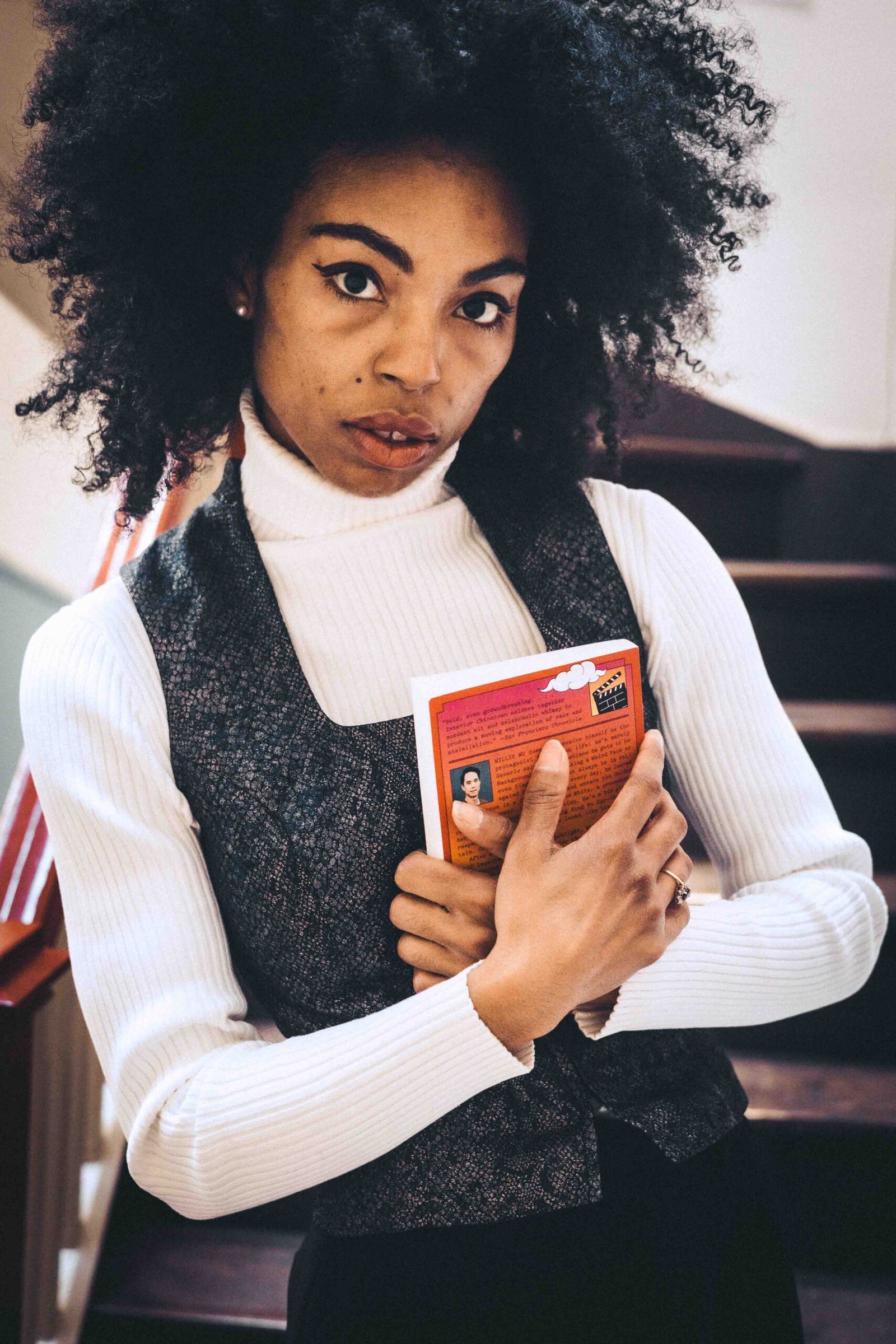 Close-up portrait of an art girl winter look featuring thrifted layers, natural makeup, and a book held close during a reflective moment.