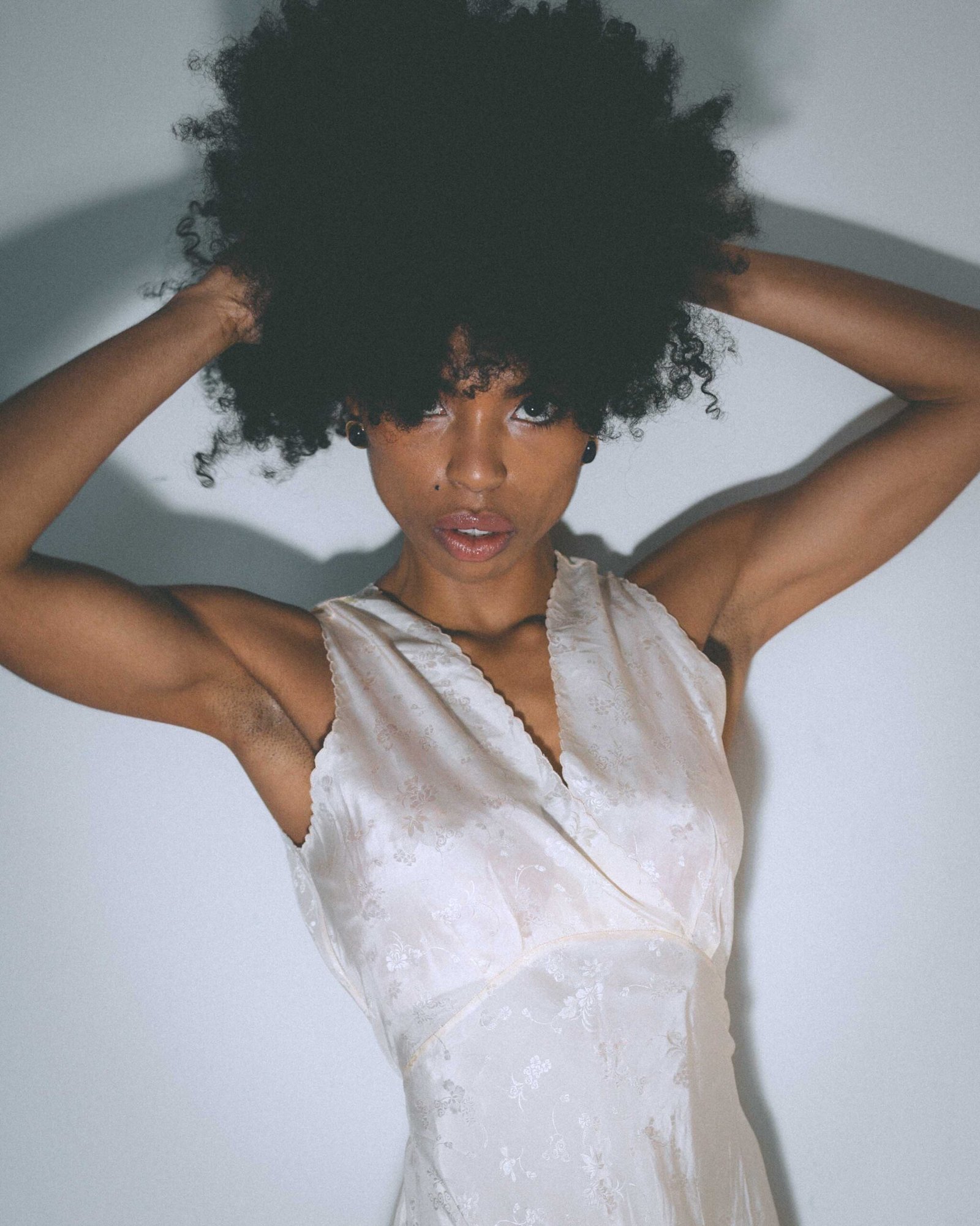 Art girl winter portrait featuring a vintage ivory slip dress, photographed indoors with soft light and an intimate, editorial feel.