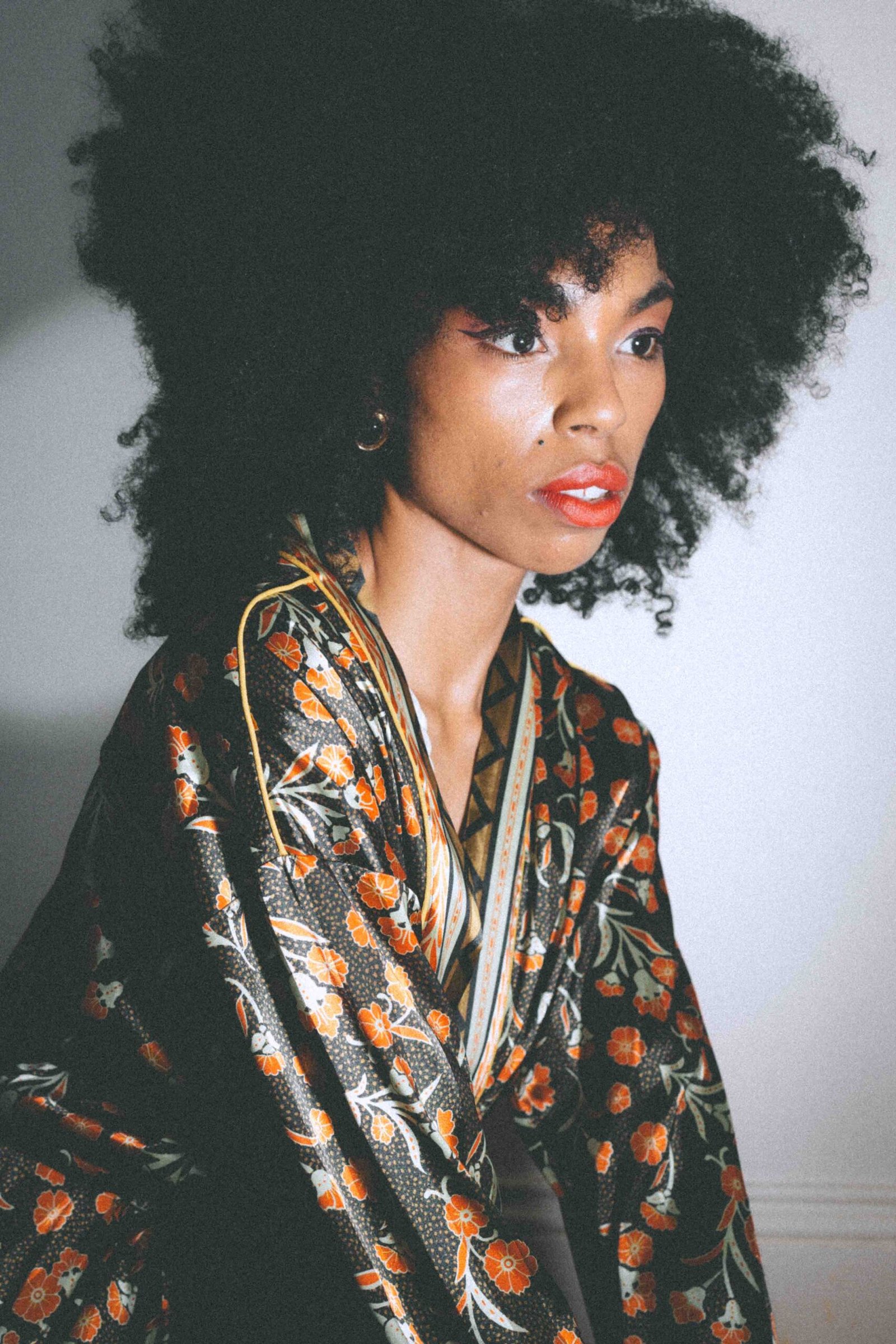 Art girl winter portrait featuring a thrifted floral robe and red lipstick, photographed indoors with soft light and a cinematic, intimate mood.