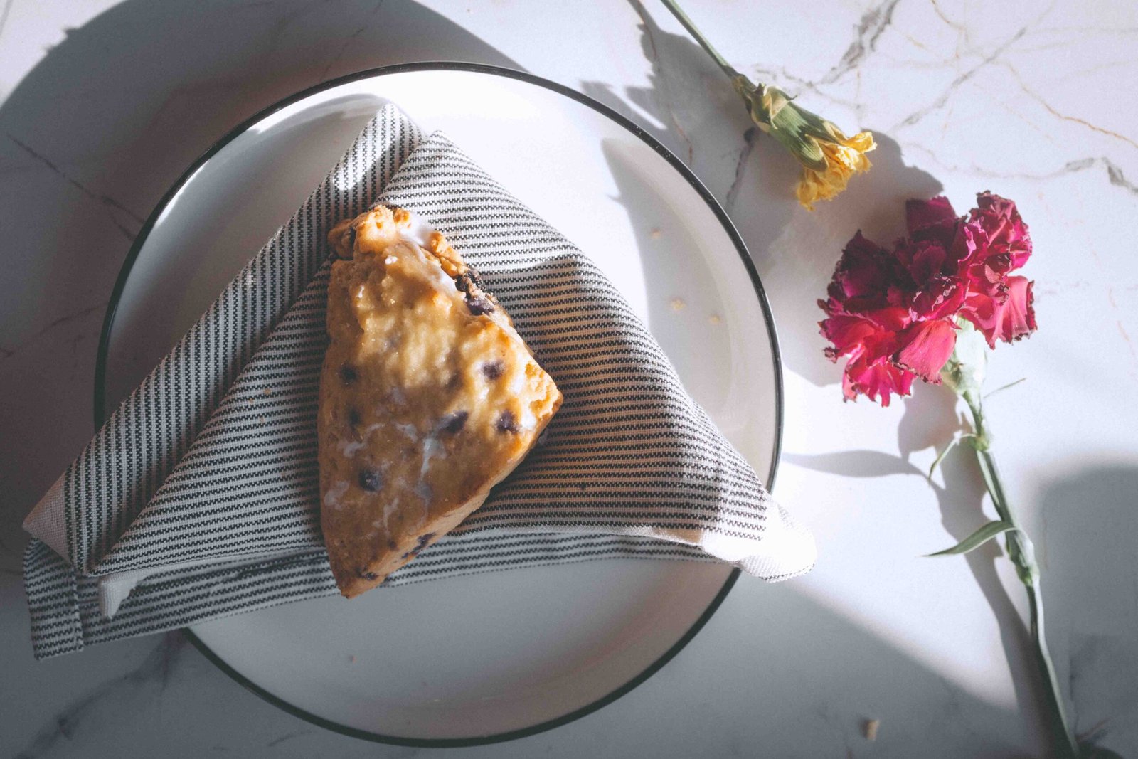 Blueberry scone on a plate with flowers, representing a simple everyday luxury at home.