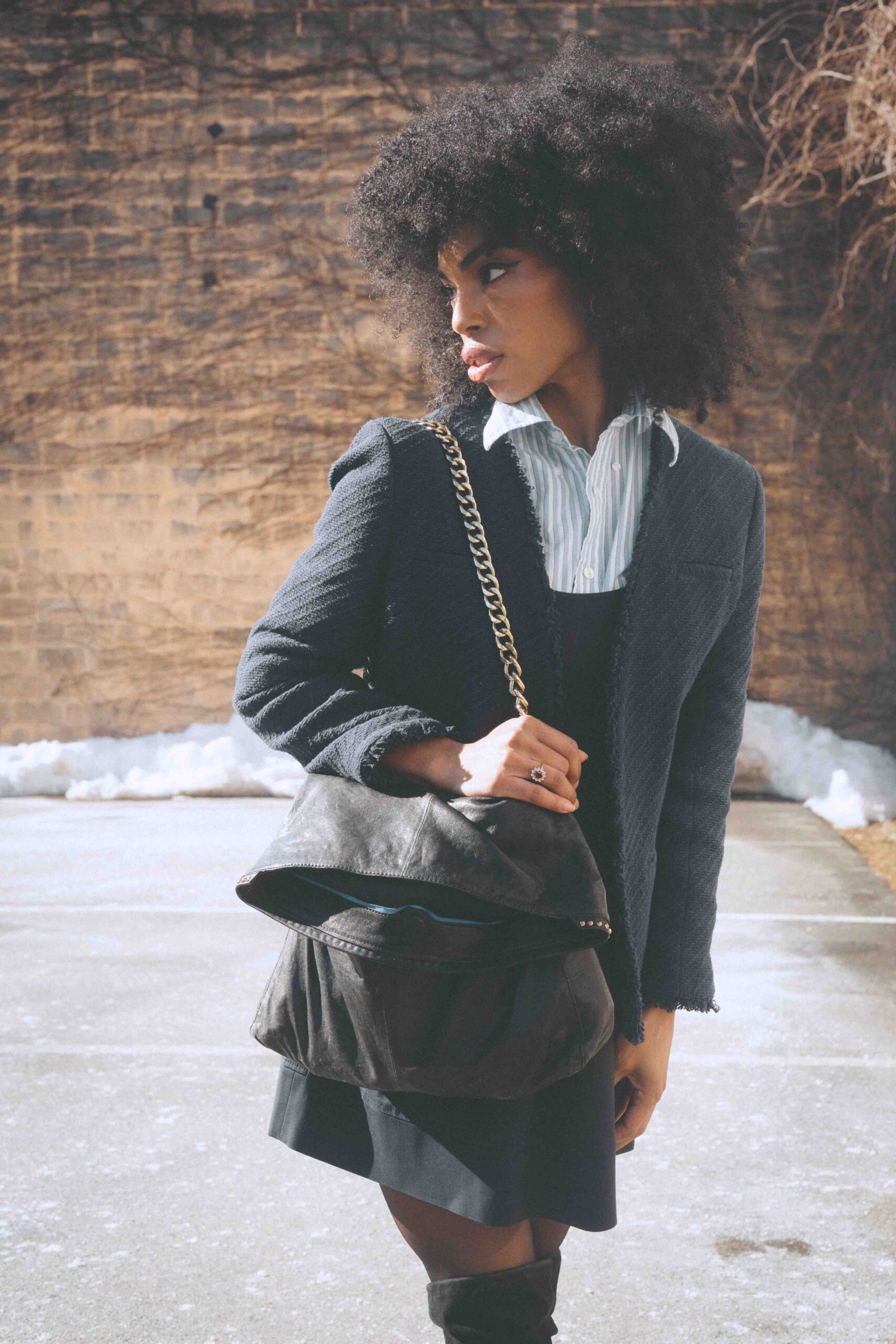 Thrifted art girl winter style featuring a structured blazer, striped shirt, and vintage leather bag worn by an emerging artist in New York.