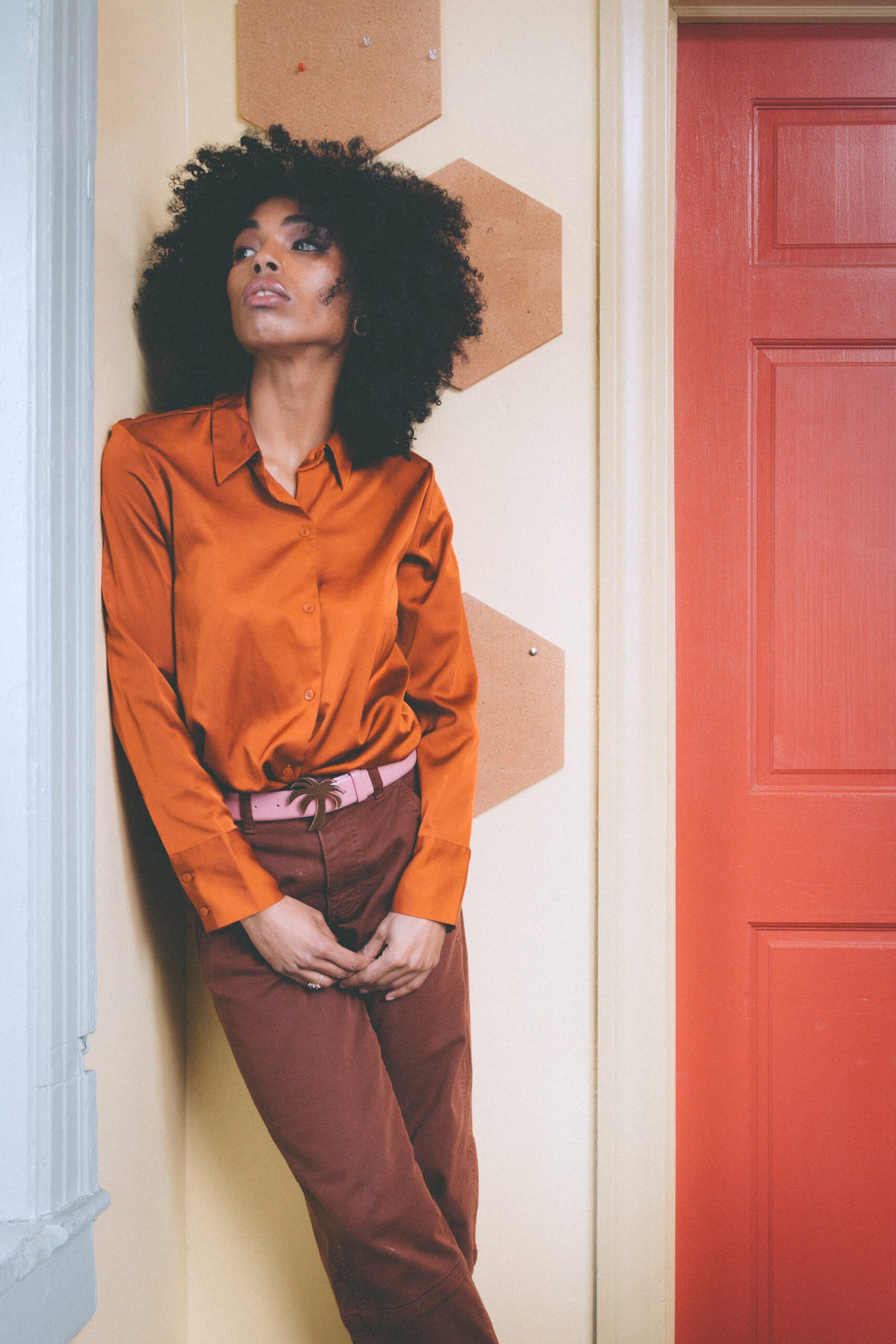 Woman in a warm-toned outfit leaning against a wall, capturing modern femininity and Valentine’s Day introspection.