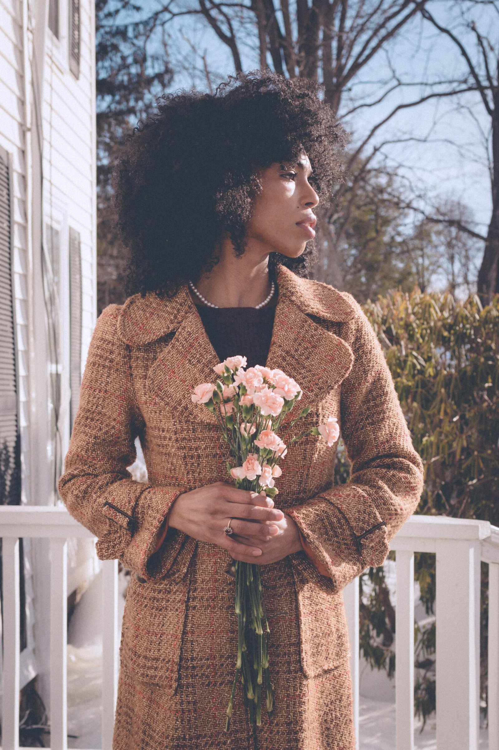 Woman holding flowers and looking into the distance on Valentine’s Day, capturing a quiet moment of reflection and self love.