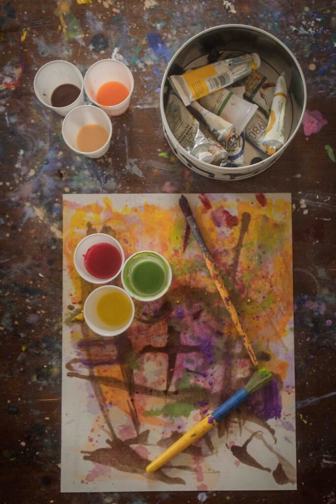 Overhead view of painting supplies and colorful artwork during creative practice session