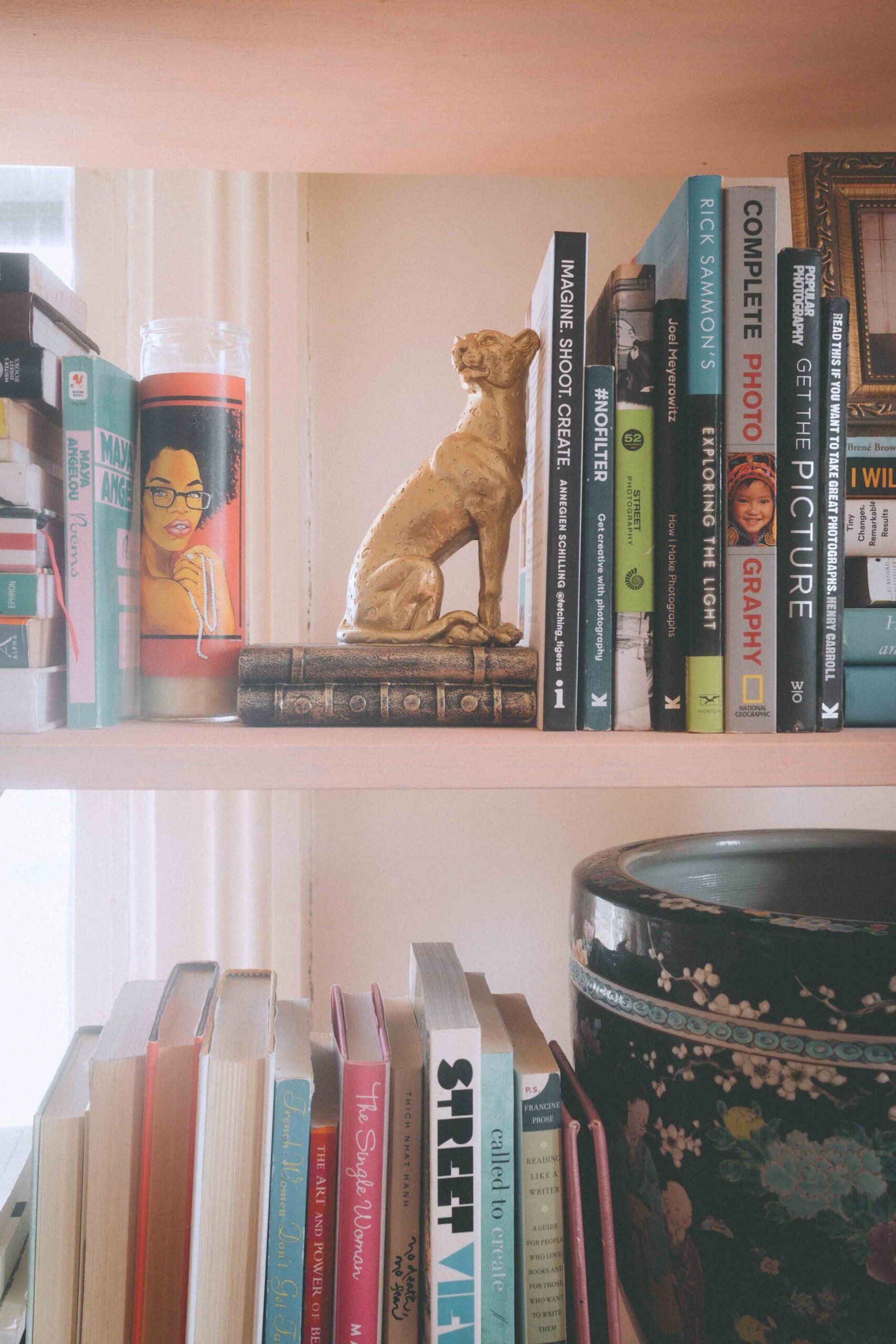 Bookshelf styled with books, candle, and decorative leopard statue in a bohemian apartment