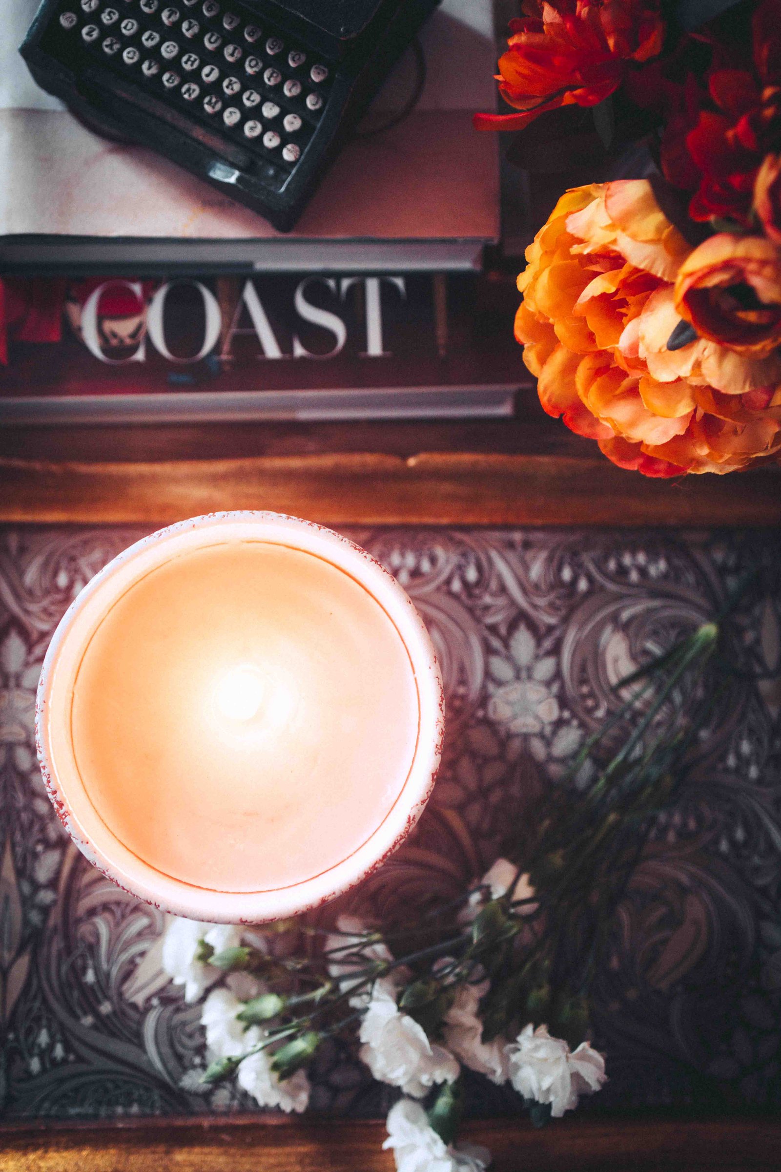 Top view of lit candle and flowers on decorative tray in a bohemian apartment