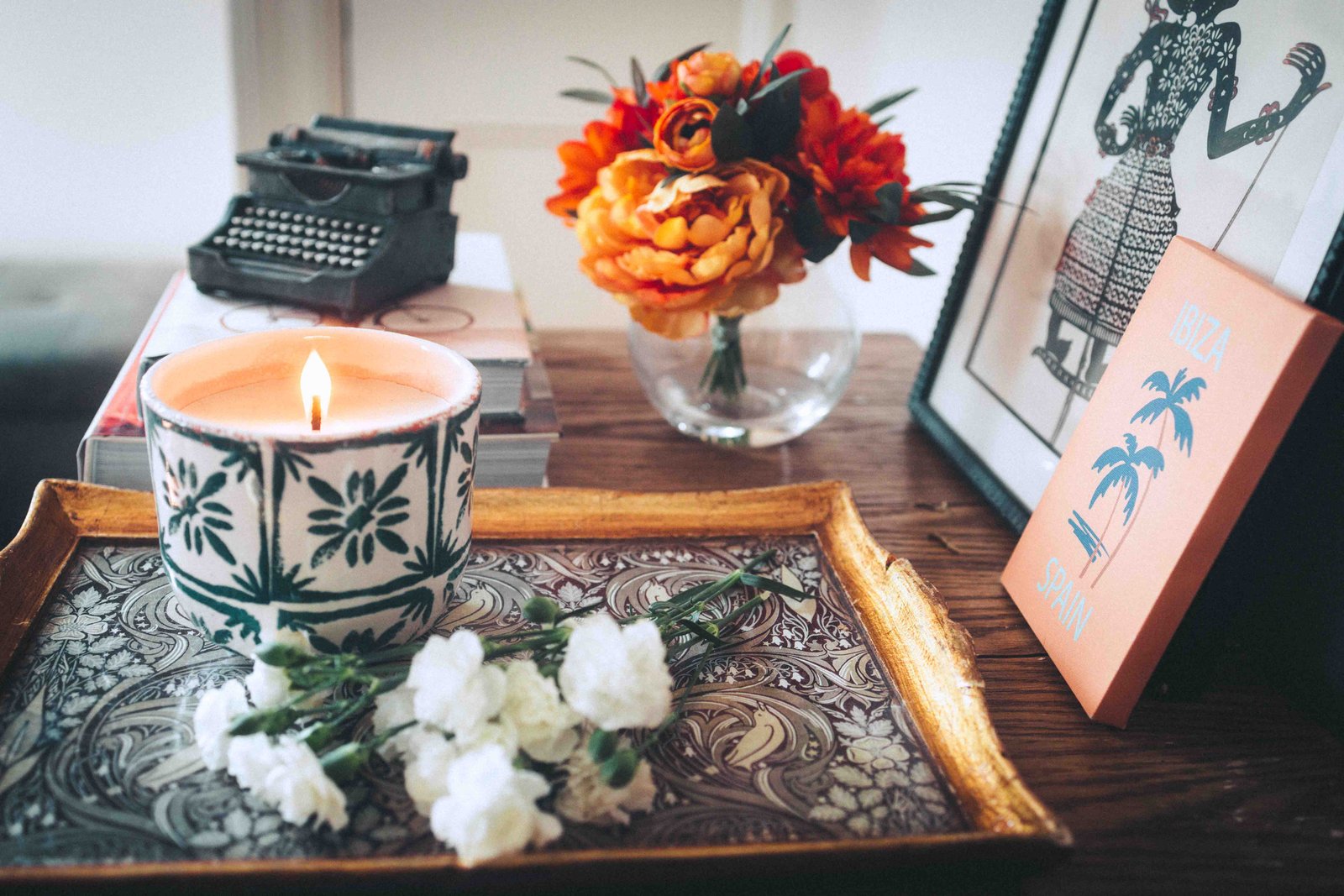 Decorative tray with candle, flowers, books, and framed art in a bohemian apartment