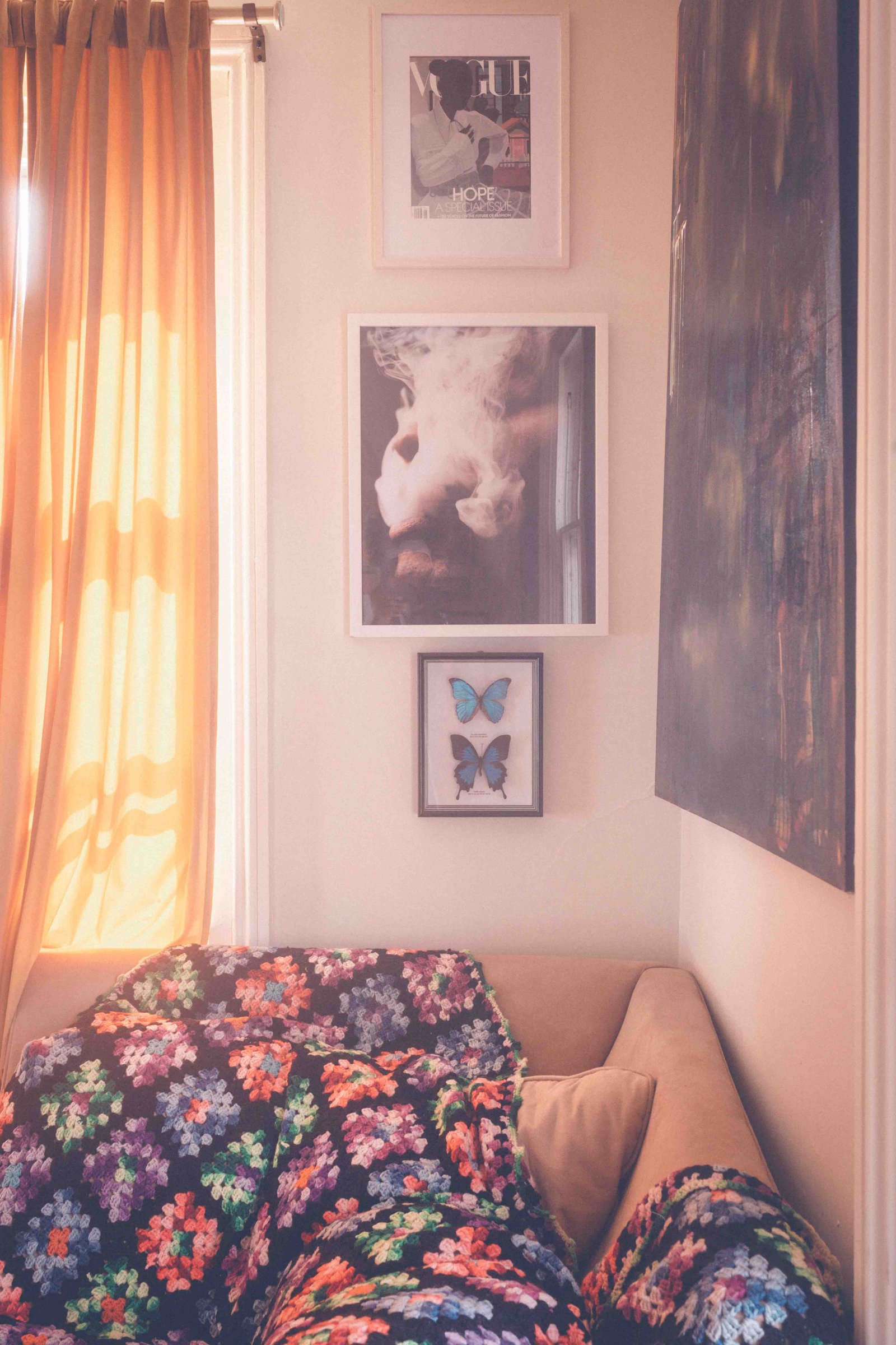Cozy bohemian apartment reading corner with crochet blanket, warm curtains, and gallery wall art