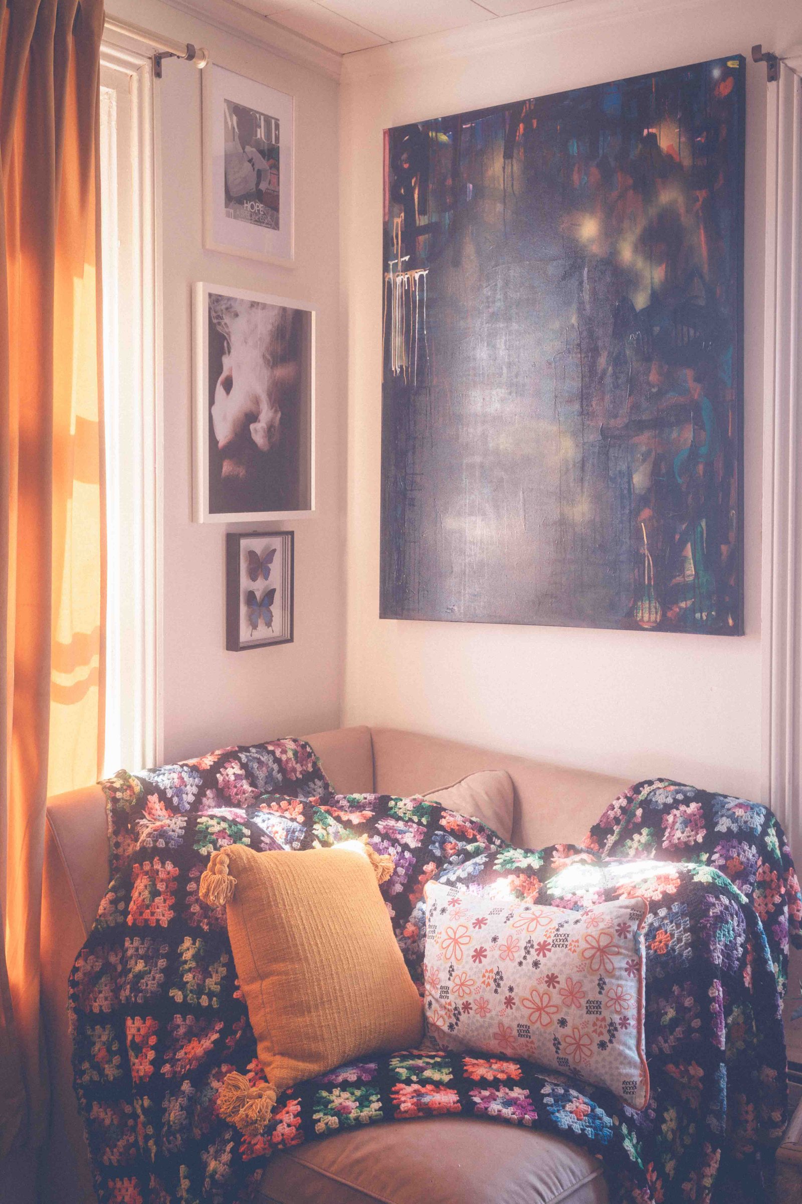 Bohemian apartment sofa styled with colorful crochet blanket, patterned pillows, and warm window light