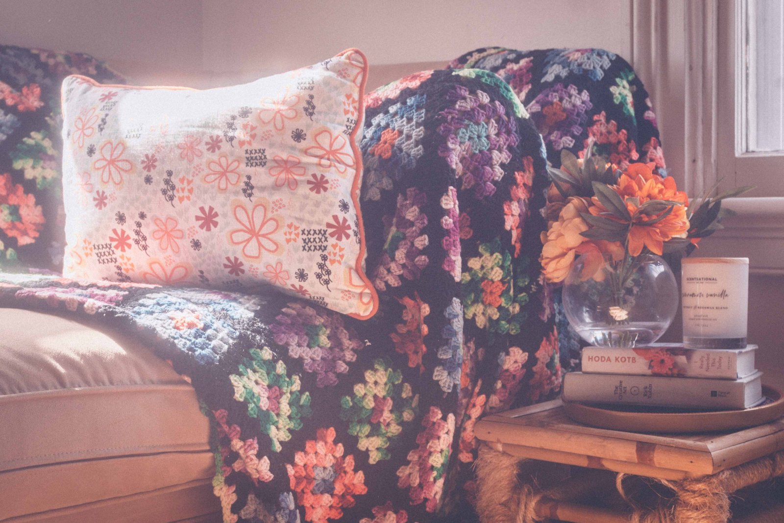 Bohemian apartment side table with flowers, books, candle, and layered textures