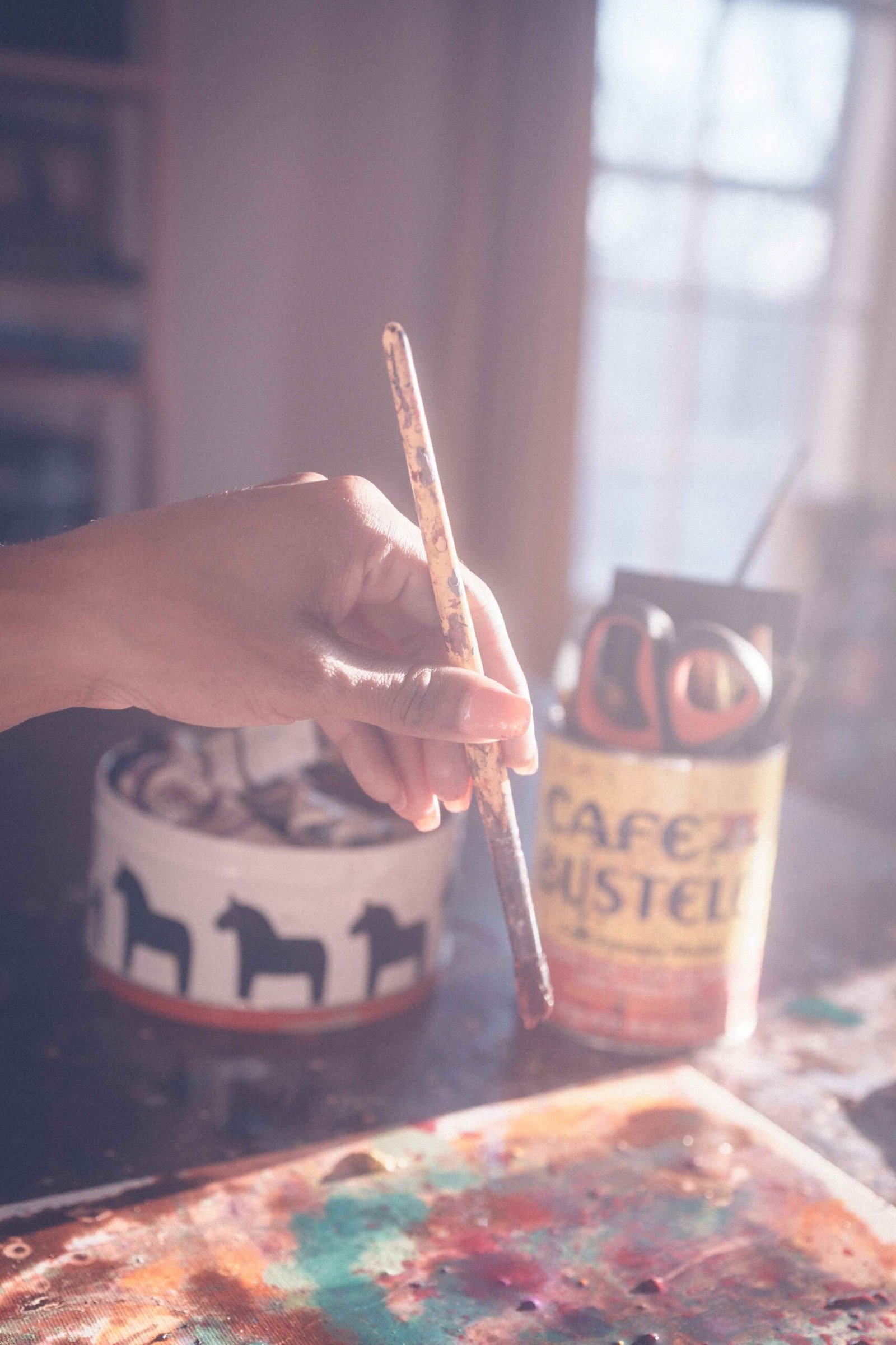 Close-up of artist holding paintbrush over abstract painting during creative practice
