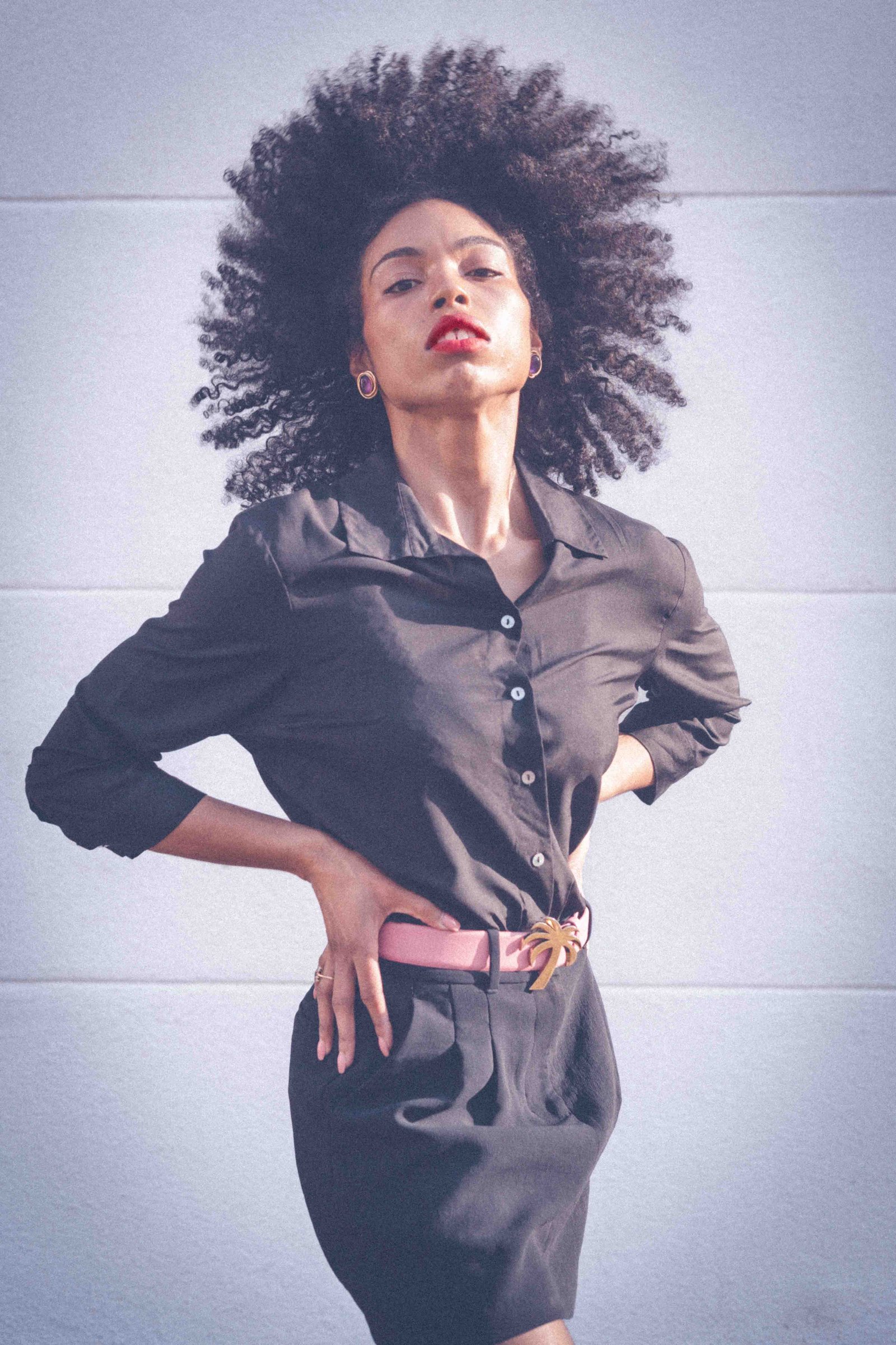 Black woman in black shirt dress with pink belt, chin raised, red lips, confidence and personal style identity