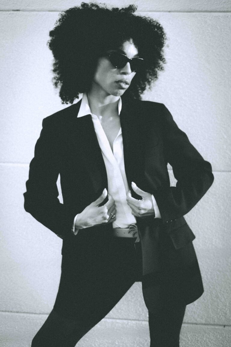 Black woman in oversized black blazer and cat eye sunglasses, black and white editorial portrait, intentional style