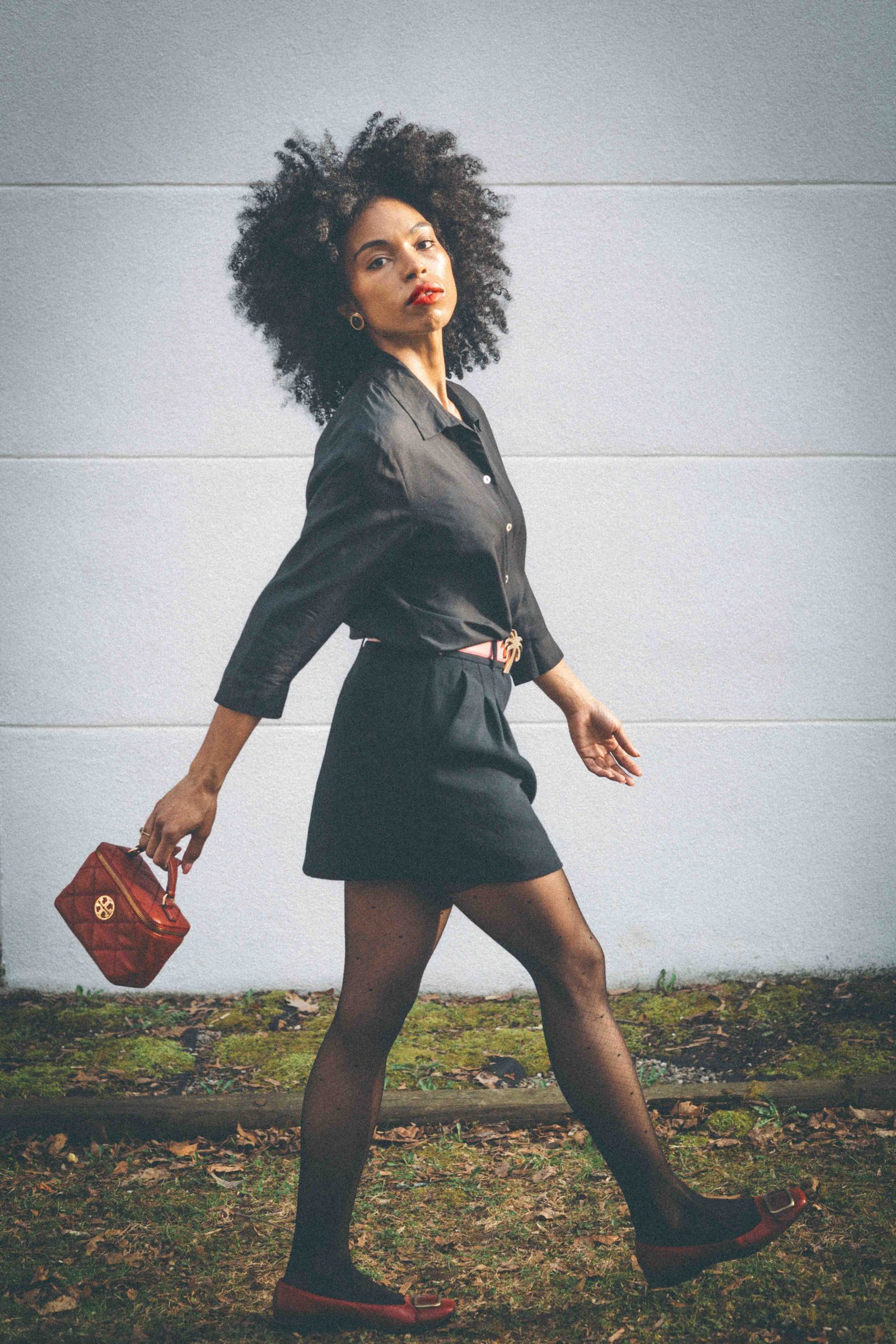 Black woman walking in black shirt dress, sheer tights and red ballet flats, how to dress like your dream self