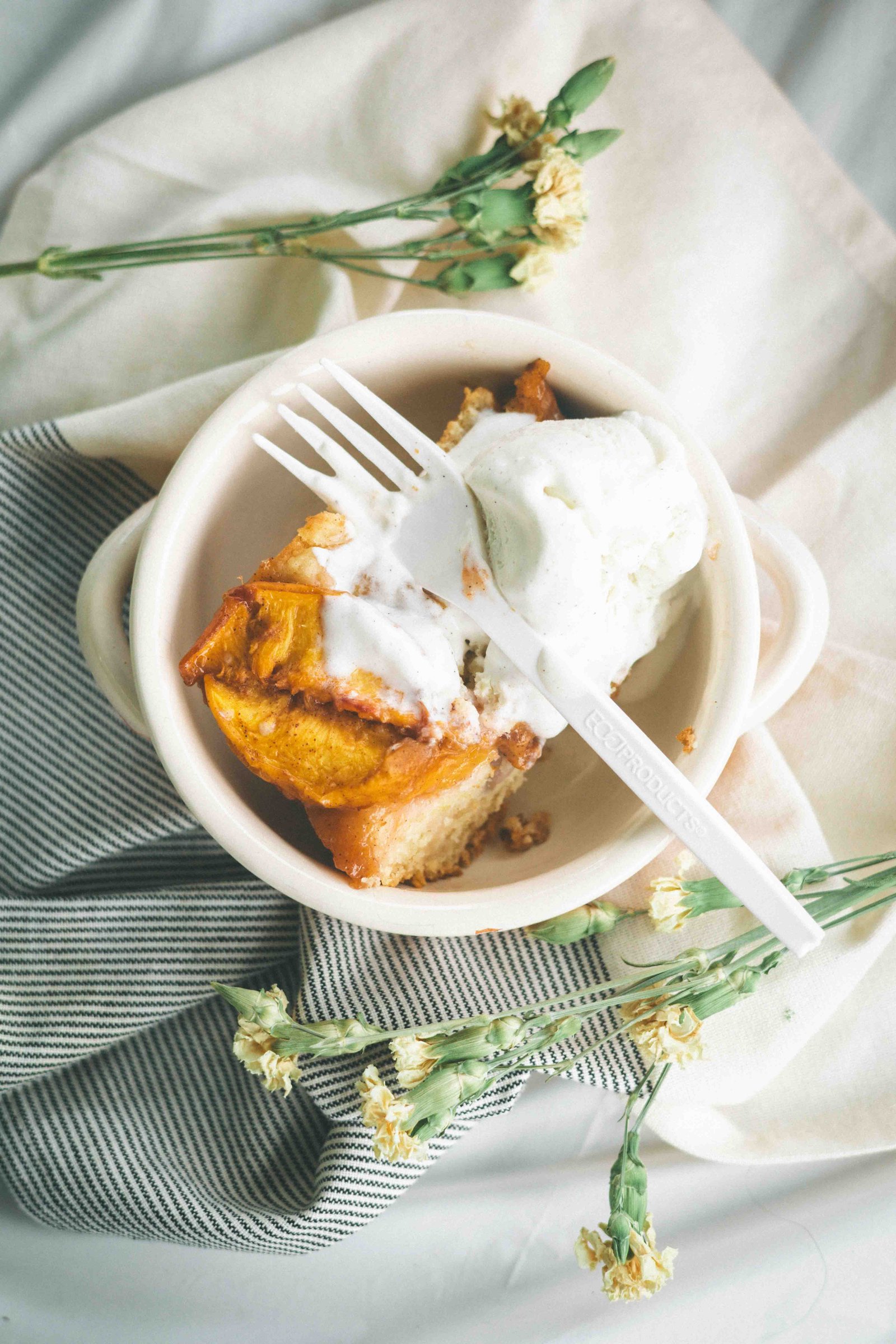 Warm brown butter peach cobbler served with a scoop of vanilla ice cream.