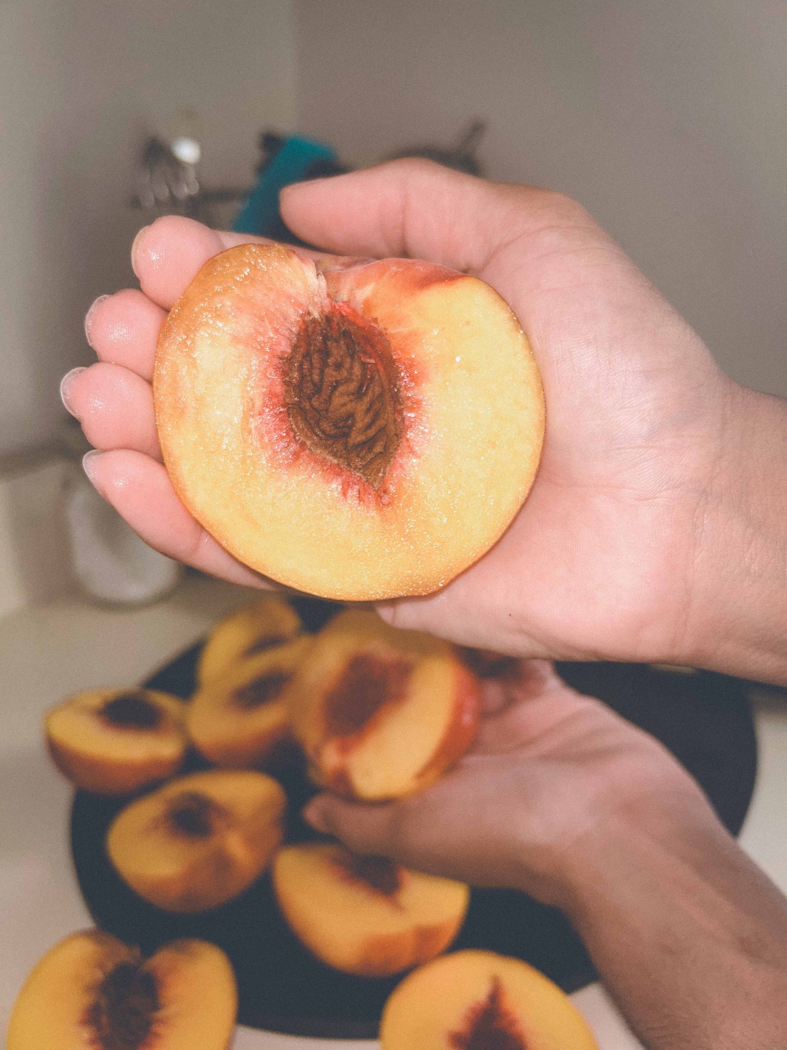 Ripe fresh peach cut in half while preparing peach cobbler.