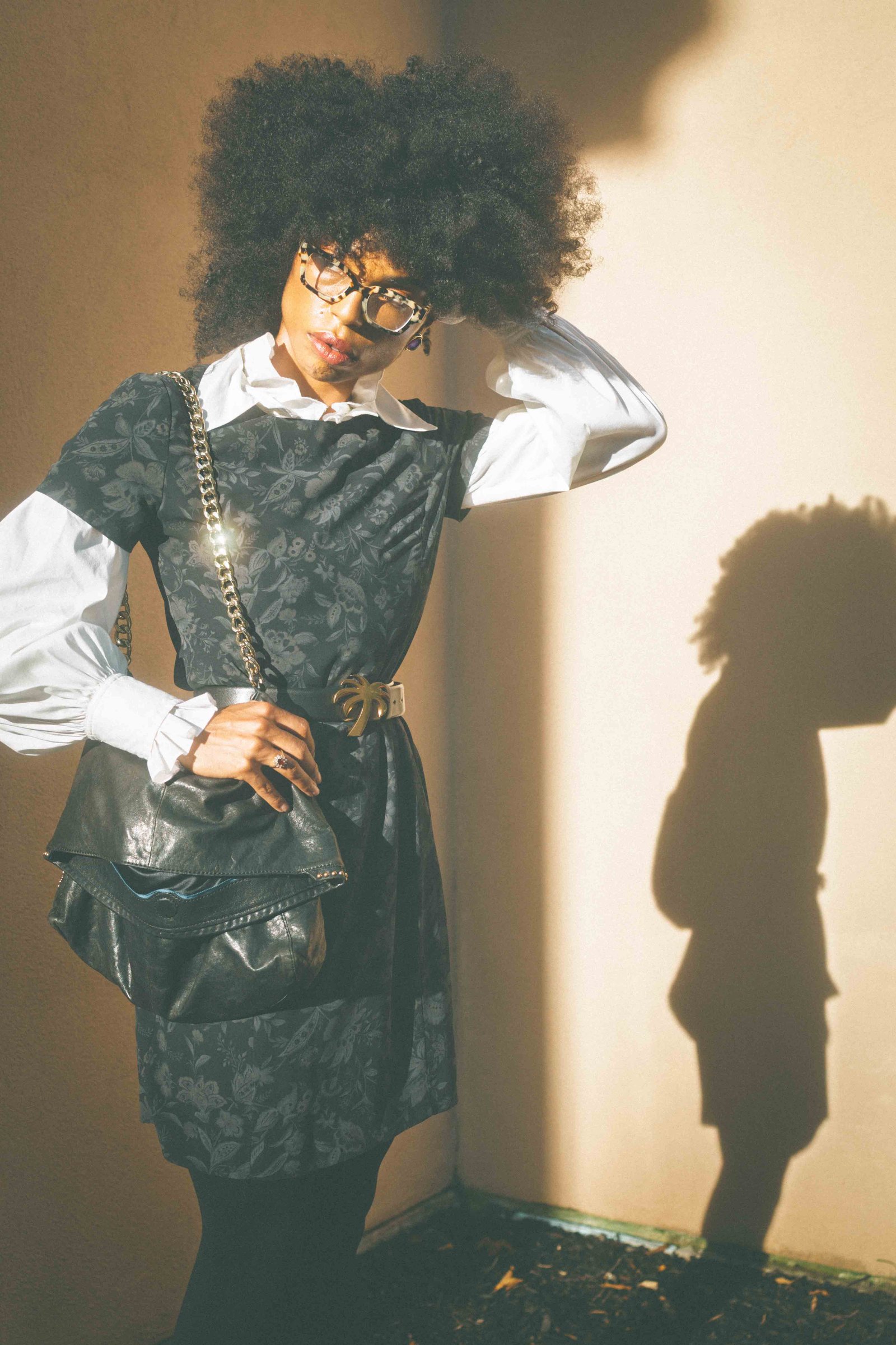 Woman wearing a dark floral vintage dress layered over a white poet blouse in dramatic evening light