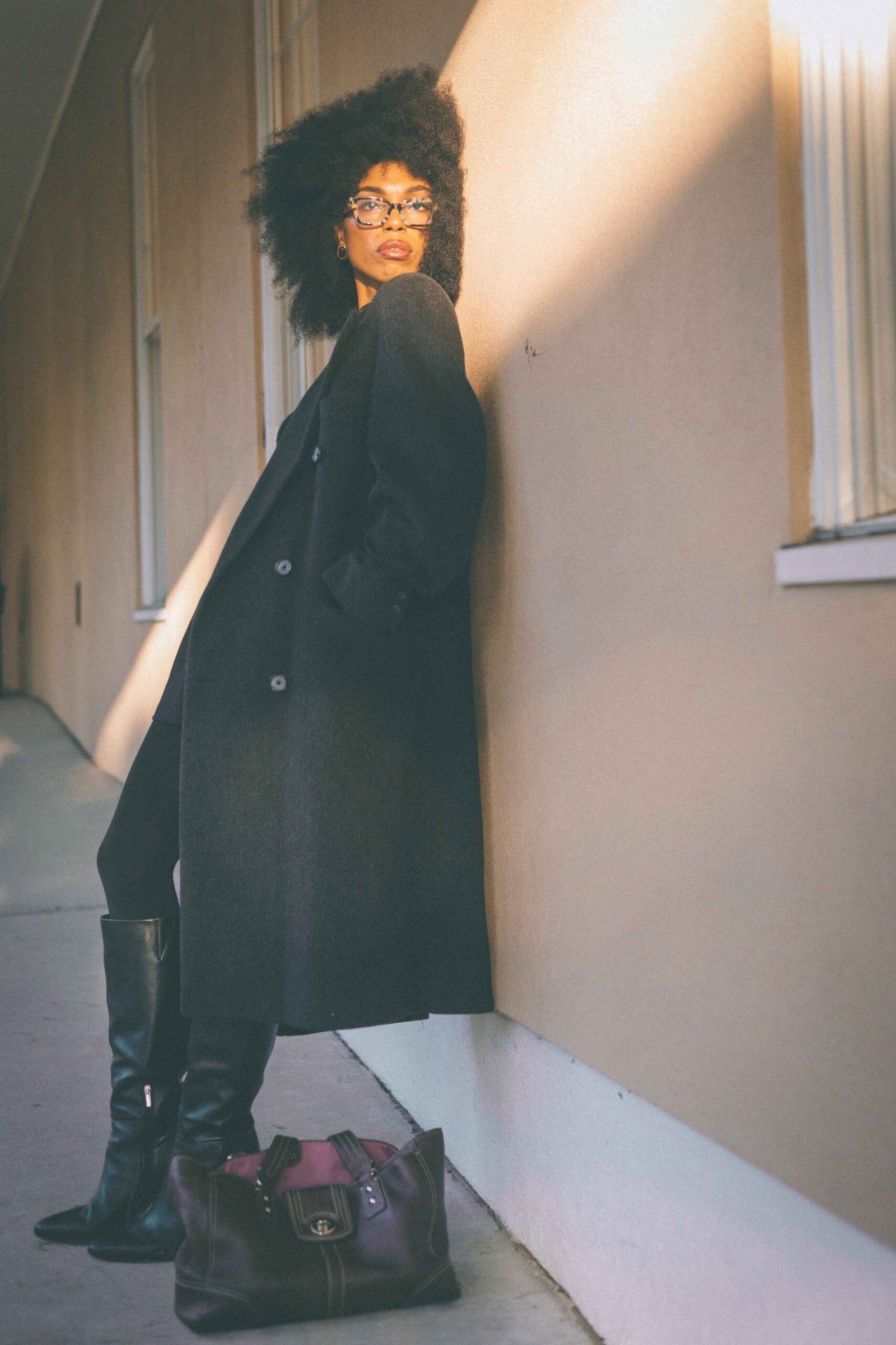 Woman wearing a charcoal wool coat over a black cashmere sweater and tailored mini skirt